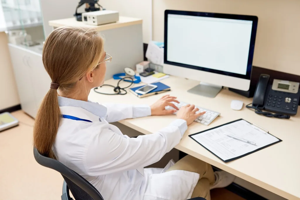 A clinician working at a computer in a medical office